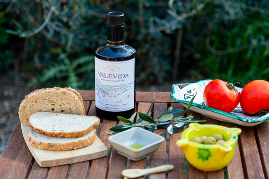 A bottle of Valèvida extra virgin olive oil beside a prepared dish on the table